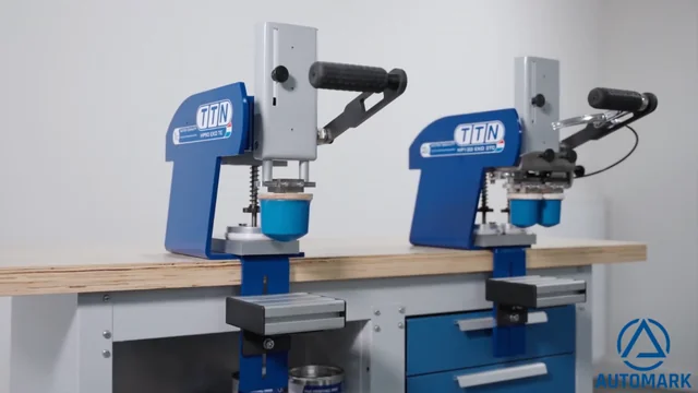 Two TTN manual pad printers, the HP90 one-color and HP120 two-color models, on a workbench, showcasing their robust design for precise industrial printing, distributed in North America by Automark.