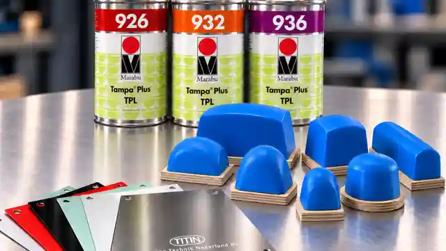 Pad printing supplies arranged on a worktable, including blue silicone printing pads, Marabu TPL ink cans, and colored metal printing plates